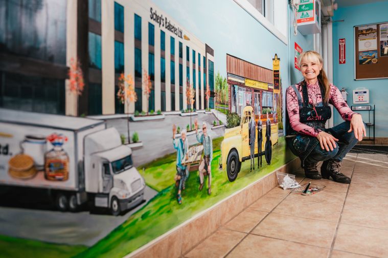 Stella Jurgen has hand-painted store-fronts of local businesses in a mural at the Tillsonburg Regional Airport.